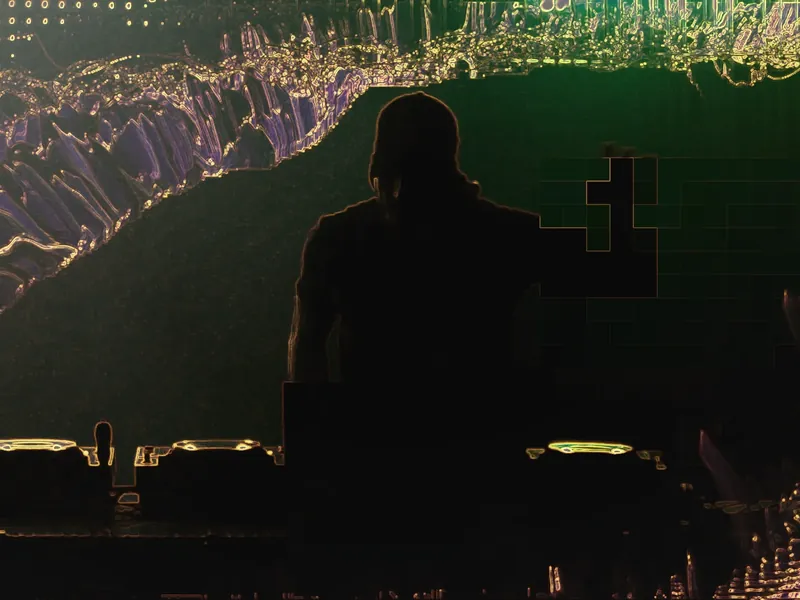 A DJ clip silhouetted against shader terrain